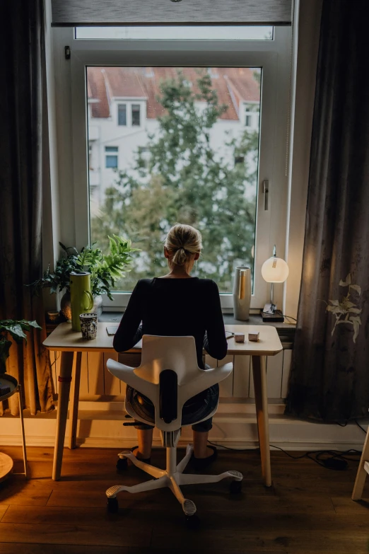 a woman is sitting in an office chair looking out the window