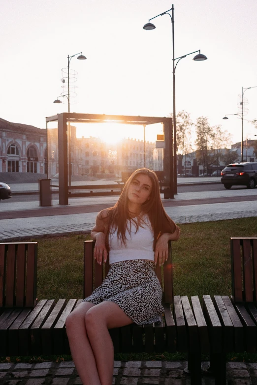 the girl sits on the bench waiting for the sun