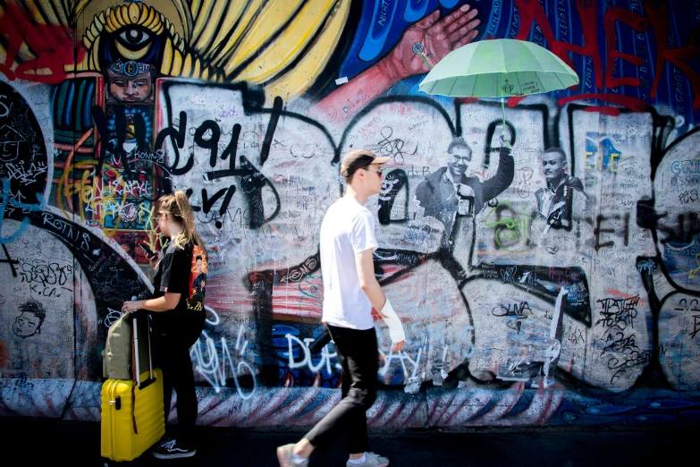 a man and woman walking with a yellow suitcase