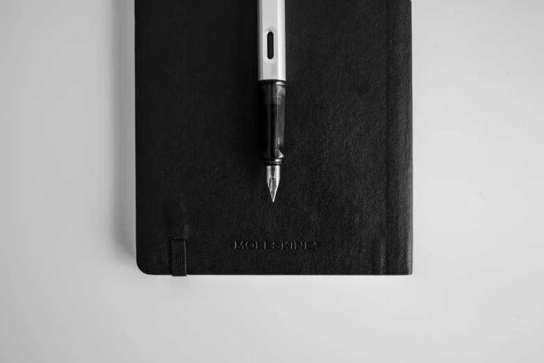 a pen resting on top of an empty black notepad