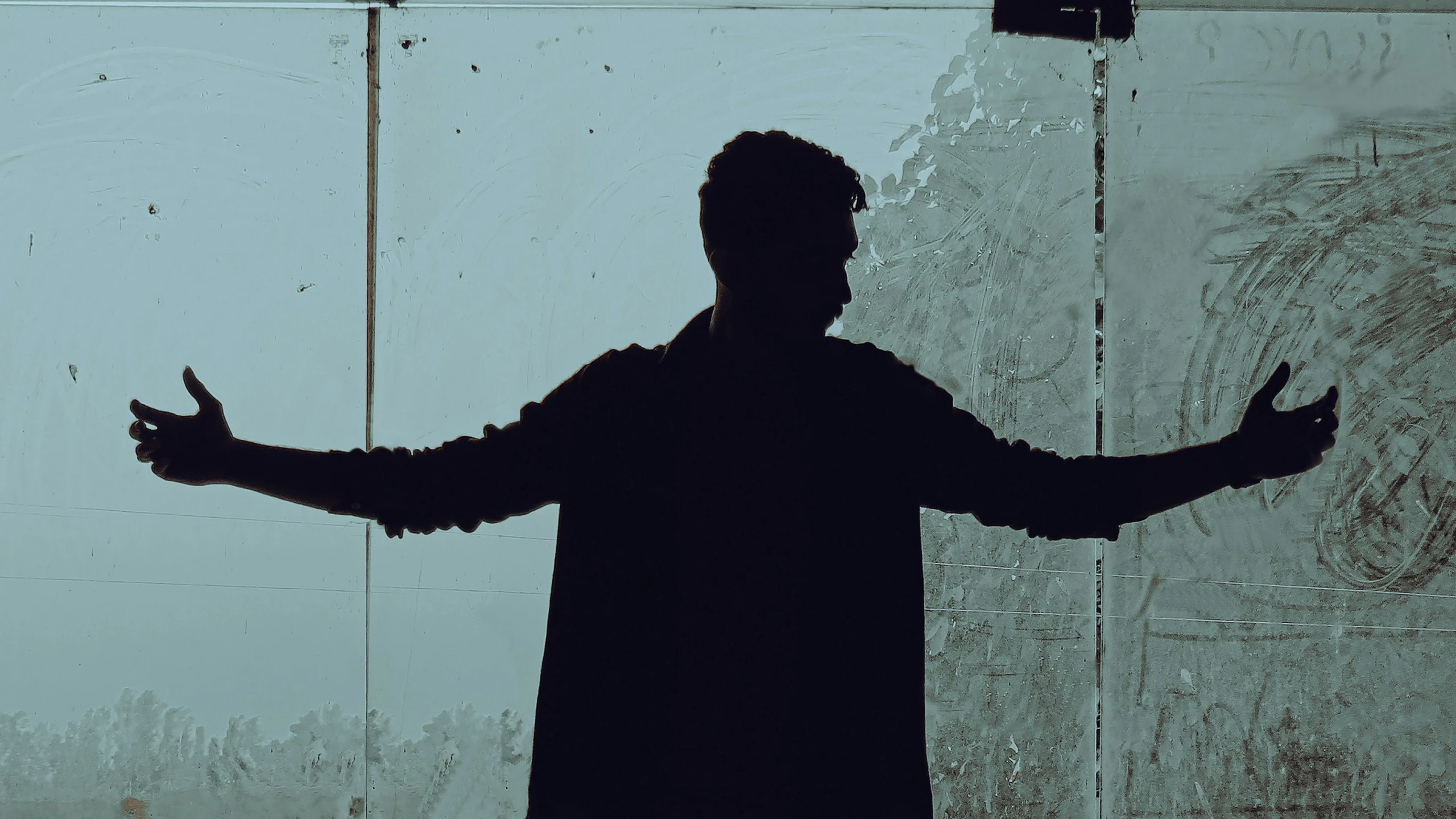 a silhouette of a man in front of a wall with graffiti on it