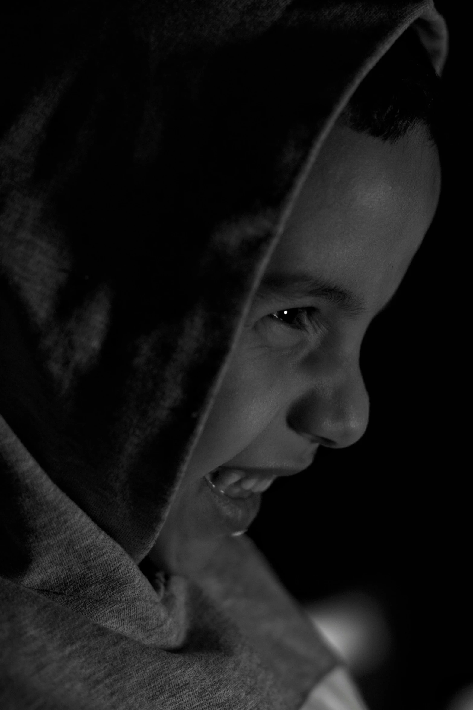 a black and white image of a young man wearing a hoodie