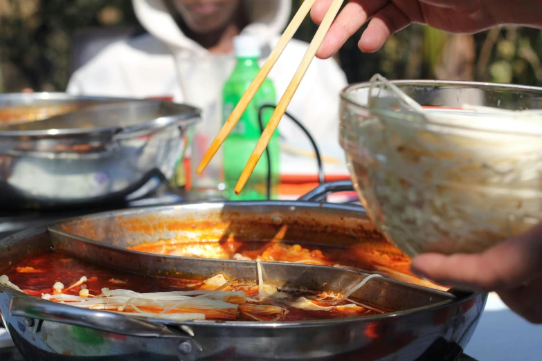 someone is cooking food on a tray with chopsticks