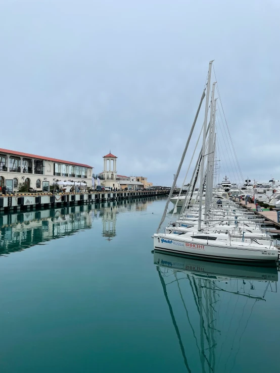 a large white sailboat floating in front of a dock