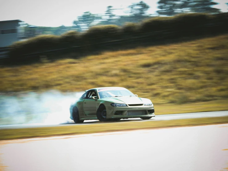 a gray sports car with blue smoke billowing out of it