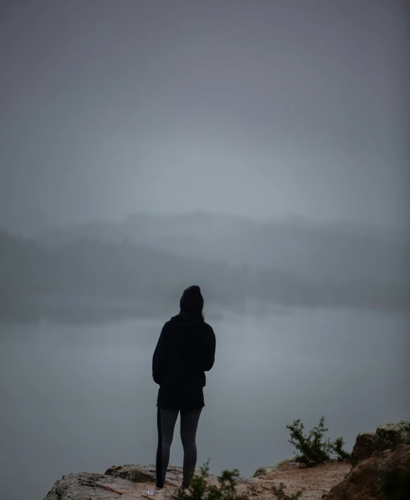 a lone person standing on top of a rocky cliff