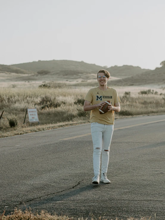 a man walking down the middle of a road with a ball