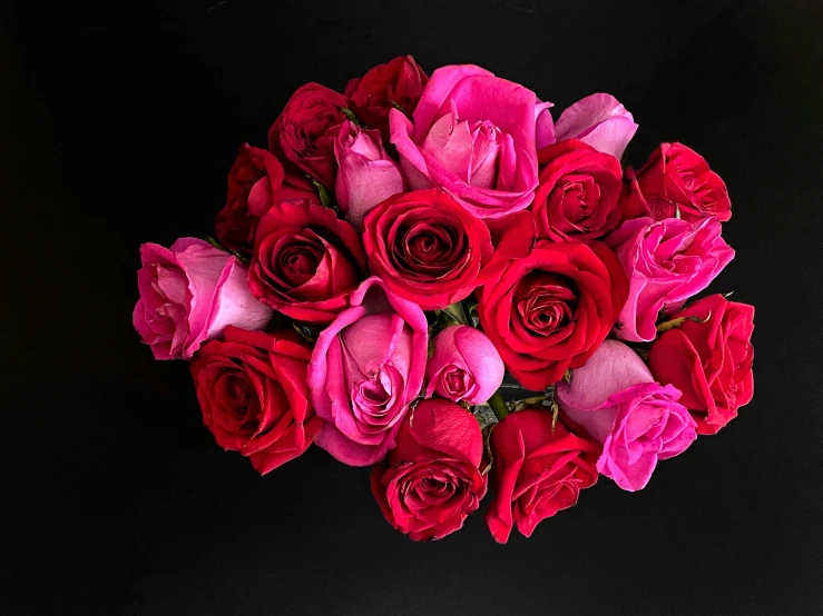 the bouquet of red and pink roses has one stem still attached