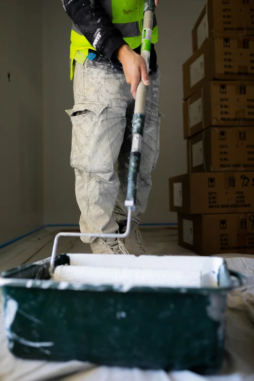 man in safety vest using a paint roller to paint