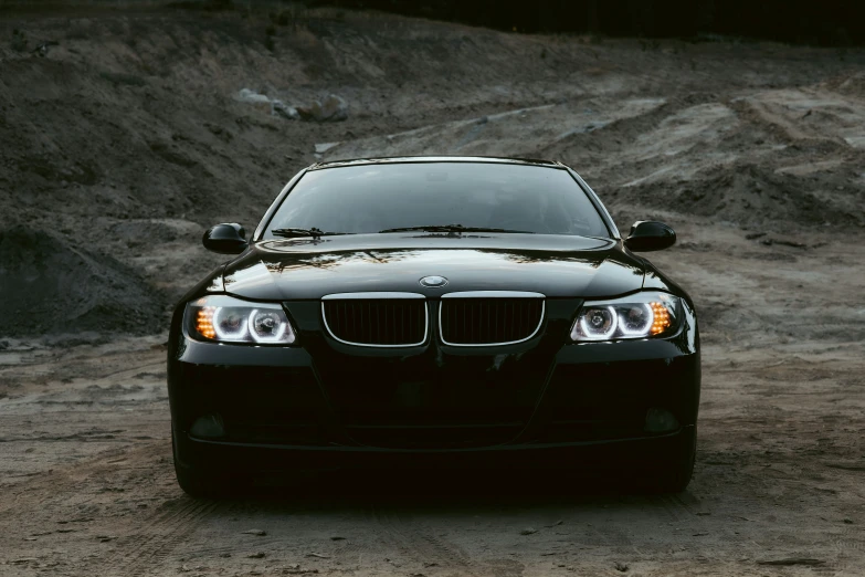 a black bmw is parked in the dirt