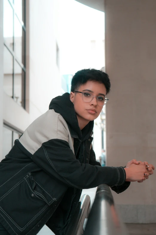 a man leaning on a fence and wearing glasses