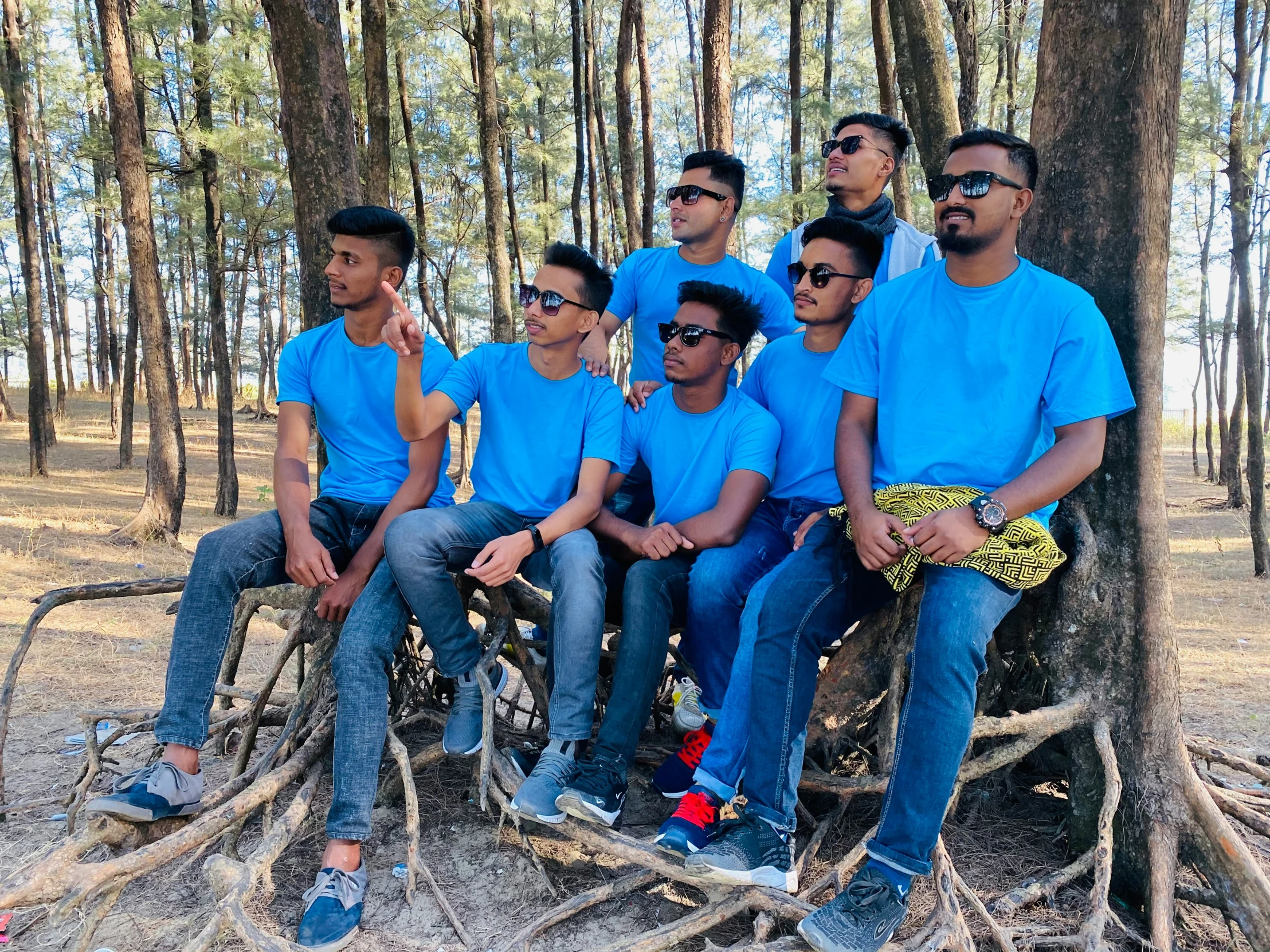 men sitting on the roots of a tree in the woods