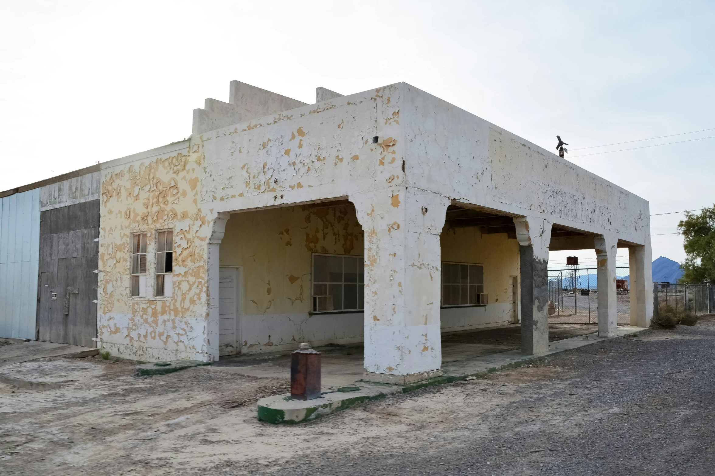 two white adobe buildings in an empty lot