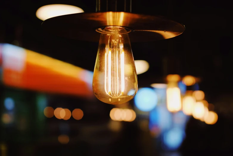 a light bulb hanging from a ceiling next to colorful lights