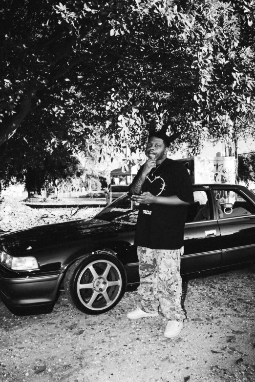 a man standing in front of a car that is parked on the side of the road