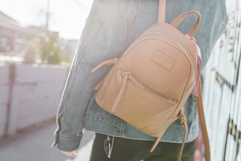 a person holding a tan backpack on their back