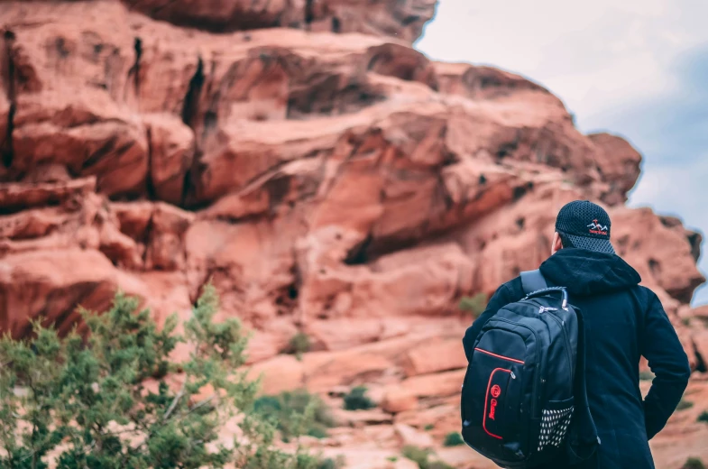 a man stands in front of a big rock