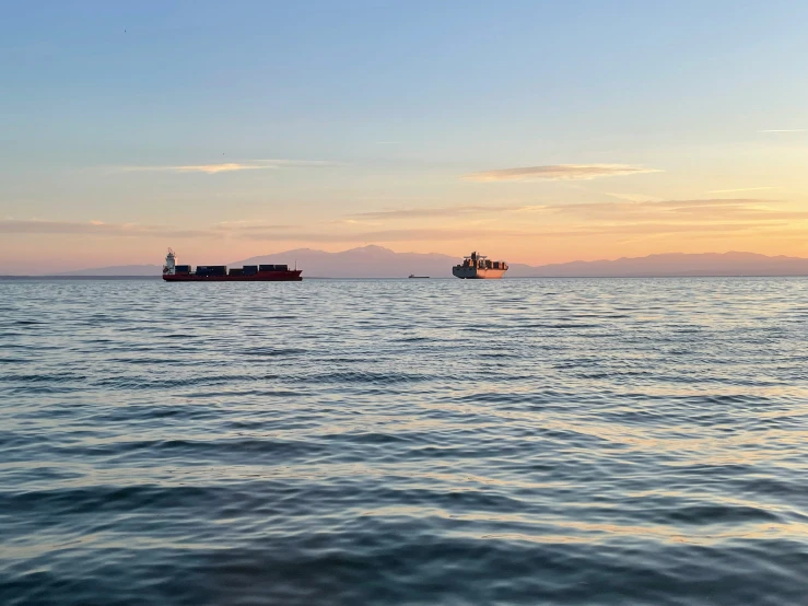 cargo ship and cargo ship are in the distance during the sunset