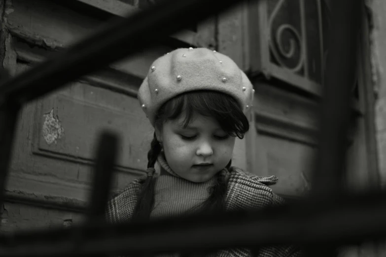 small child wearing a hat while looking through bars