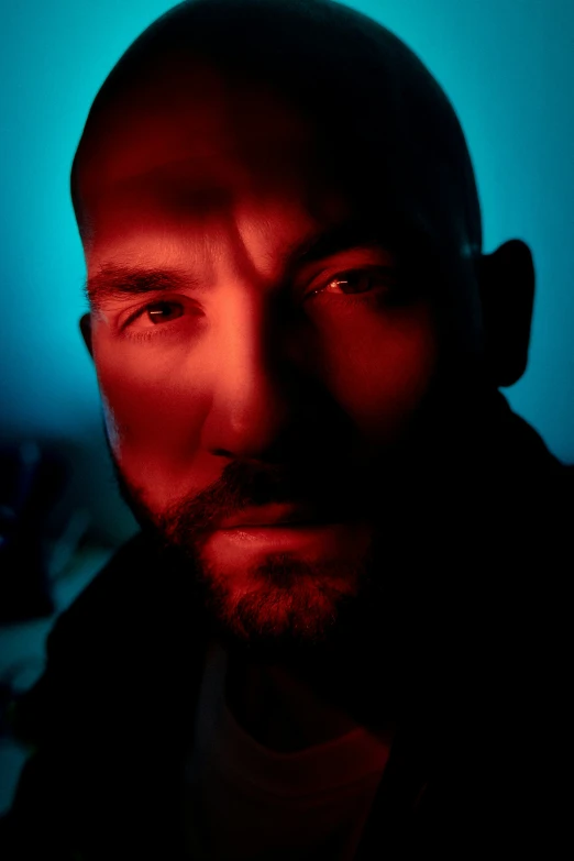 man with red lighting behind head, close up