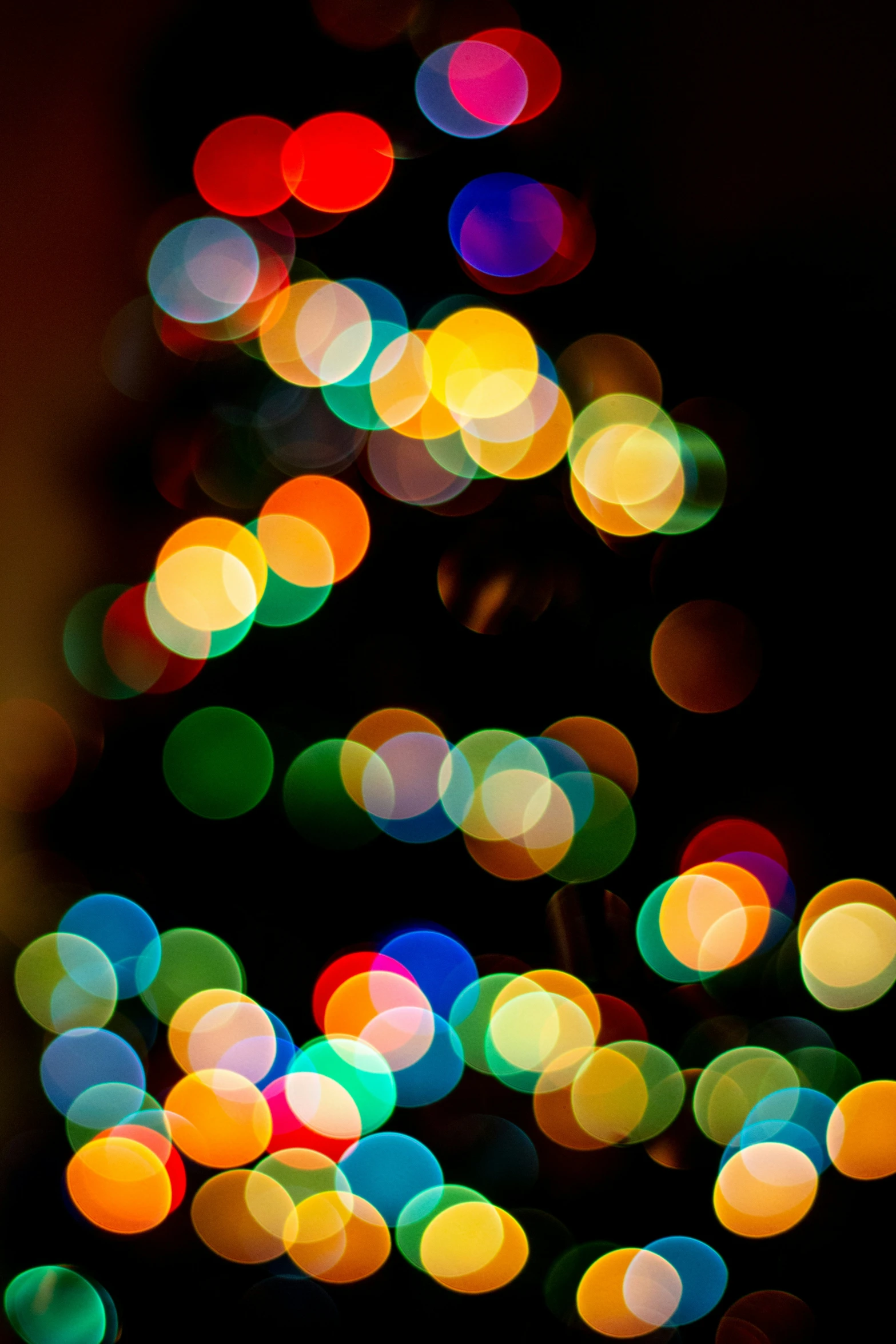 a blurry christmas tree is brightly colored in the dark