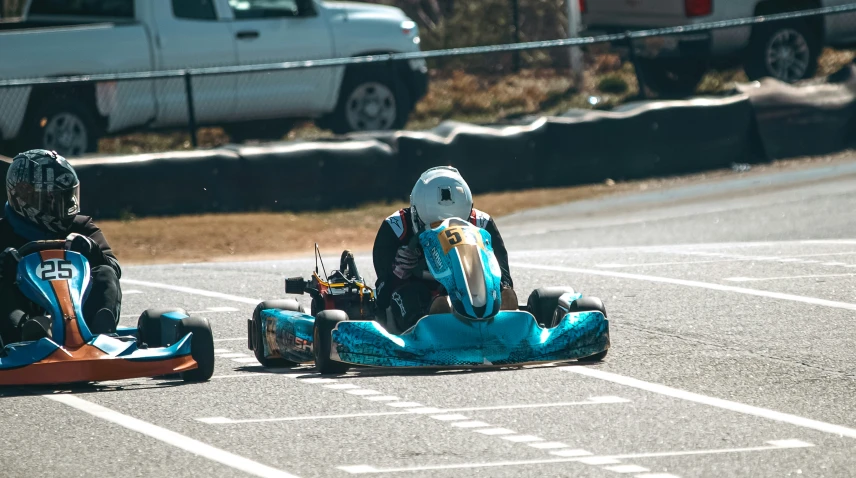 two people are in blue go carts racing down the road