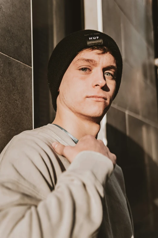 a man in grey hoodie posing by a building