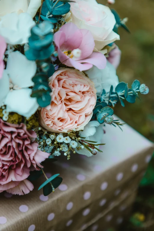 flowers and greenery sitting on top of a small white box