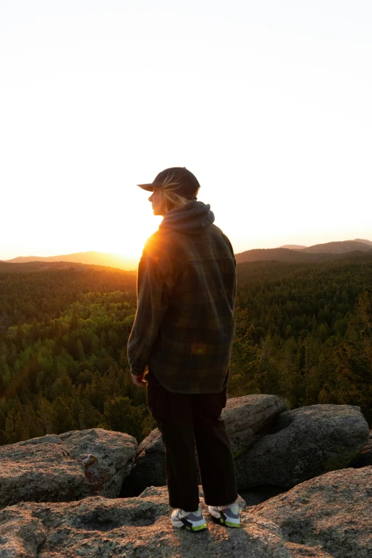 a man standing on top of a rocky hillside at sunset