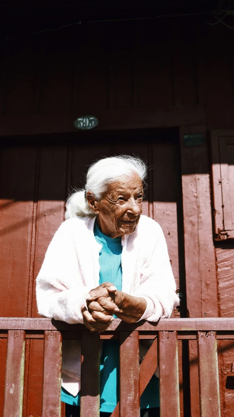 an elderly woman stands on the porch and looks off to her right