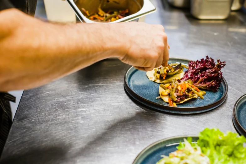 man putting food in plate on blue counter top