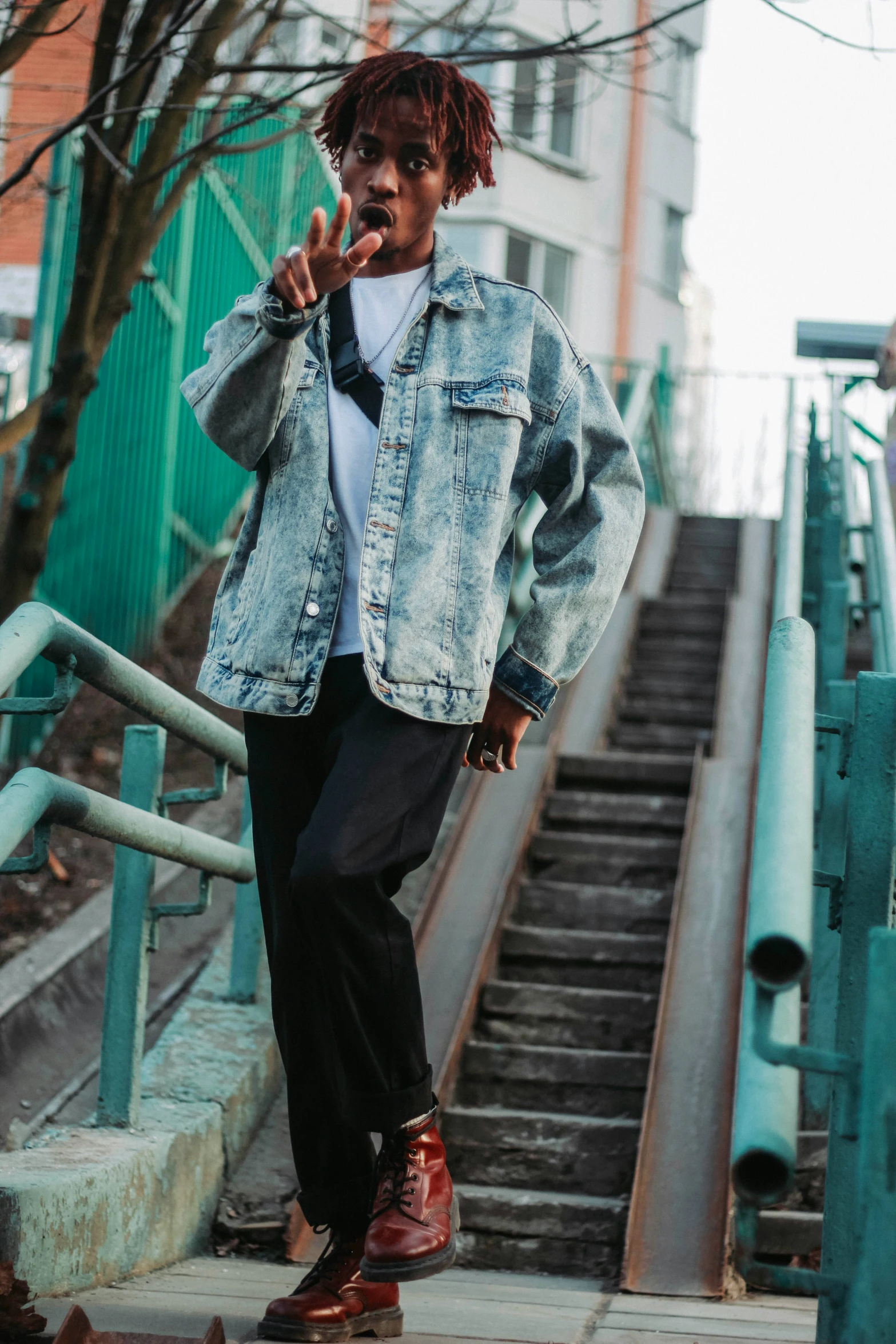 a young person in blue jean jacket standing by stairs