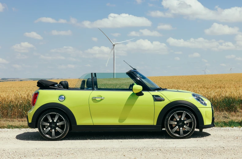 the new, lime green mini convertible is parked by the wheatfield