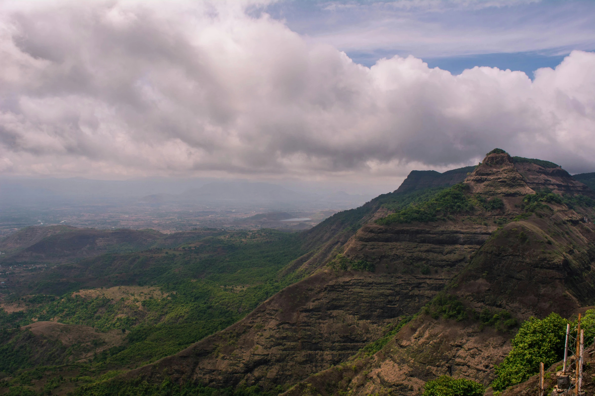 clouds roll over the mountains as one person sits on a bench