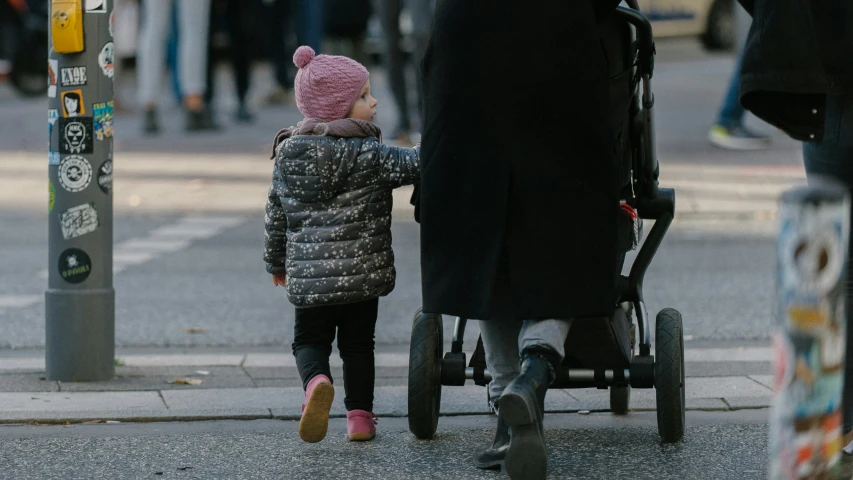 a woman with her baby standing next to a stroller