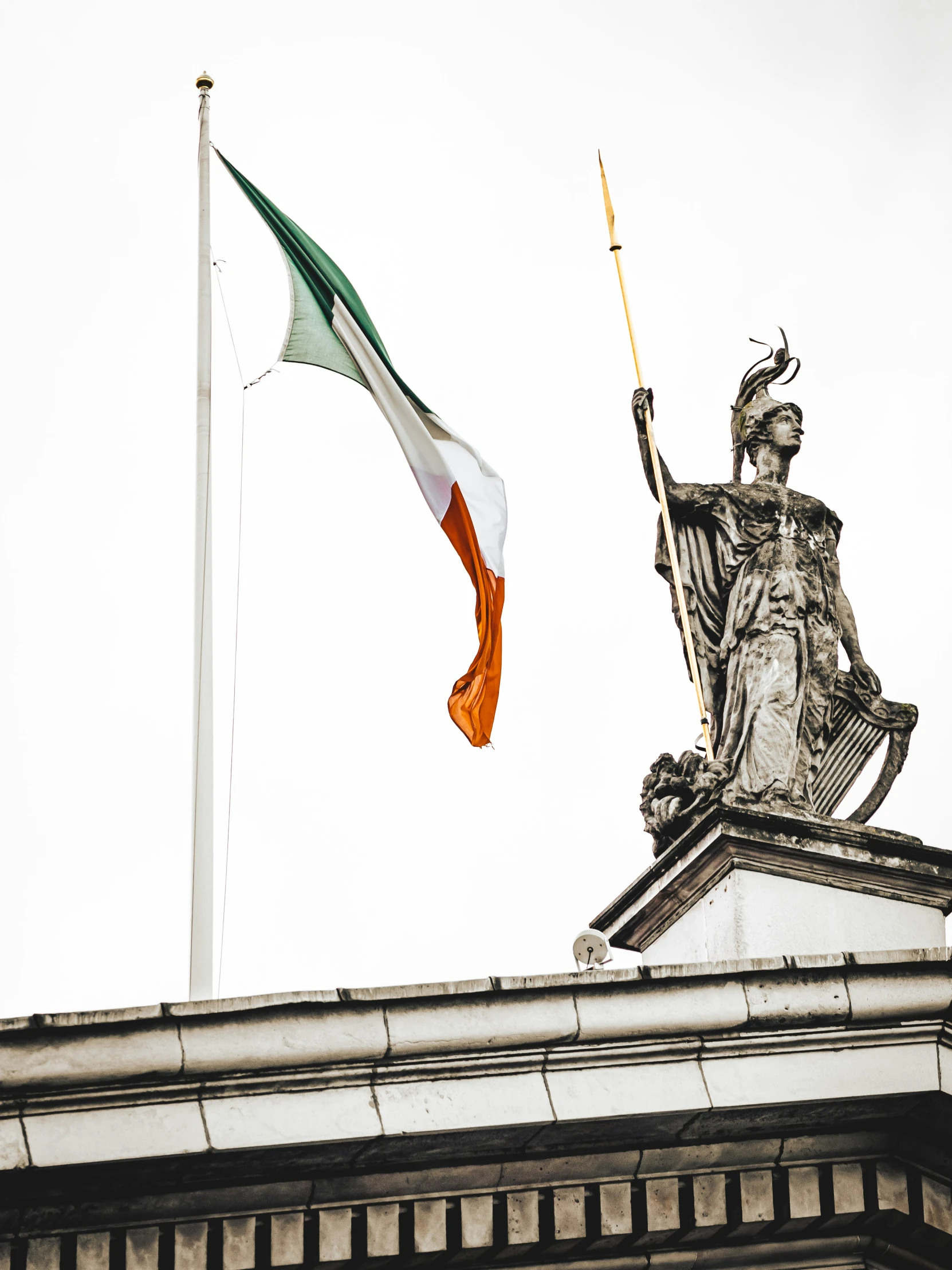 two flags flying high next to a statue