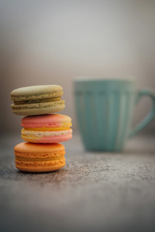 several macarons stacked on top of each other in front of a coffee cup