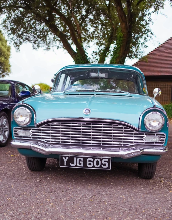 an antique car with the hood up sitting on gravel