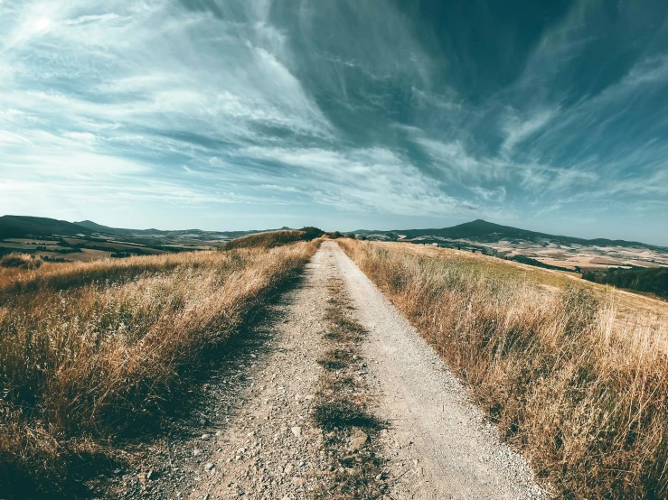 a dirt road stretches toward a scenic landscape