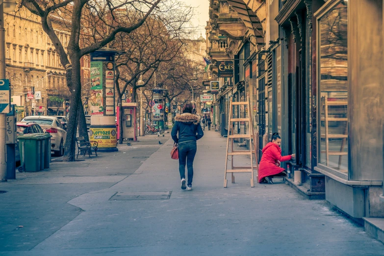 two people walking down the sidewalk in front of a store