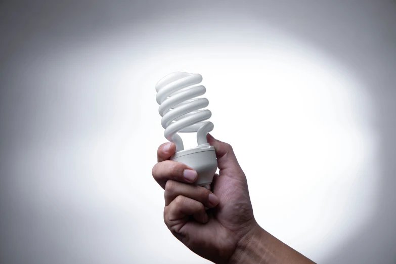 a hand holding a light bulb that is turned on