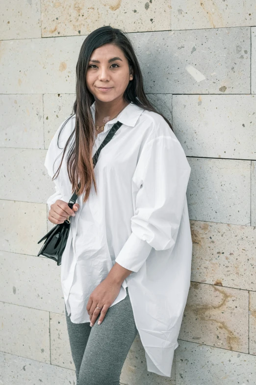 woman leaning against a wall in an off white shirt