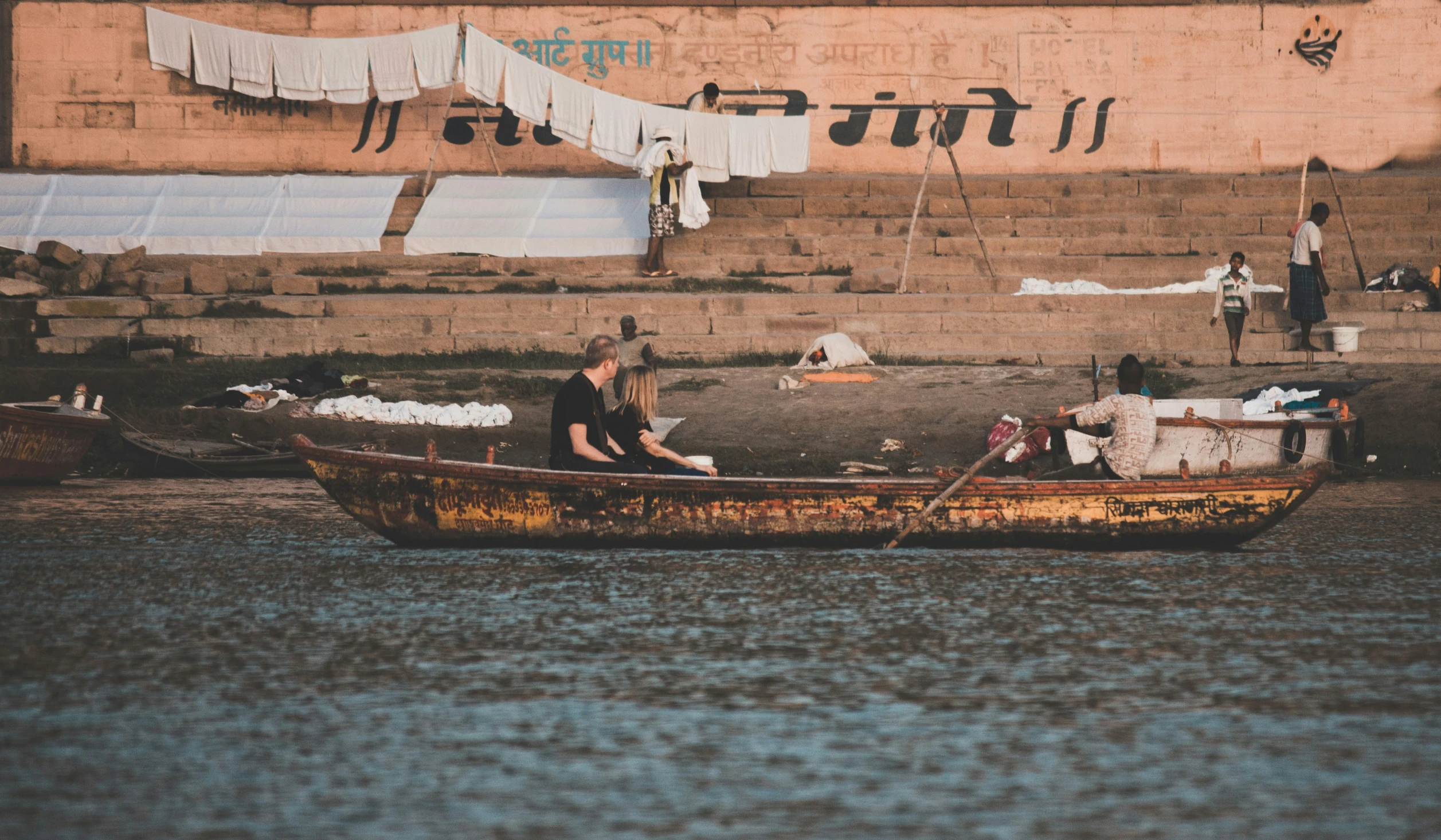 a man and woman sitting in the water in a wooden boat