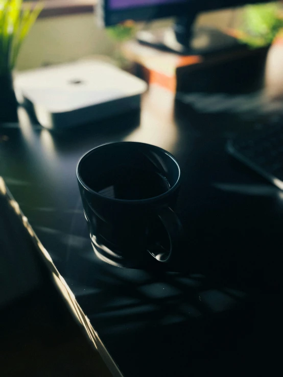 a coffee cup sitting on top of a desk next to a laptop computer