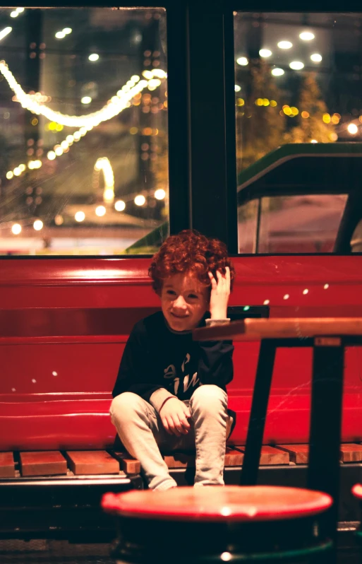 a boy sitting on top of a red bench