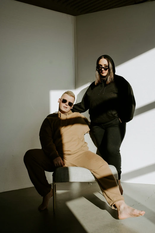 a man and woman posing for the camera with one holding his leg in a chair