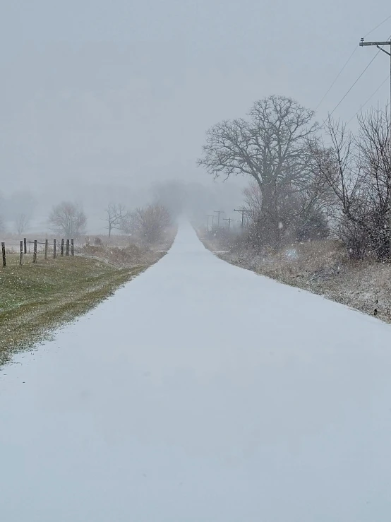 a road in the middle of a field with snow on it