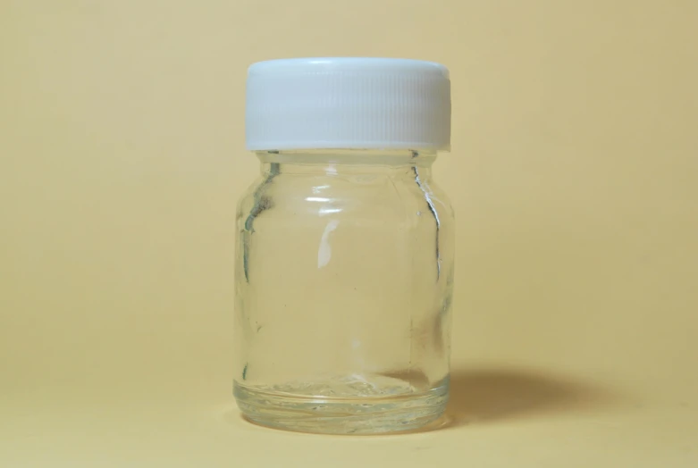 a glass bottle is on a yellow surface