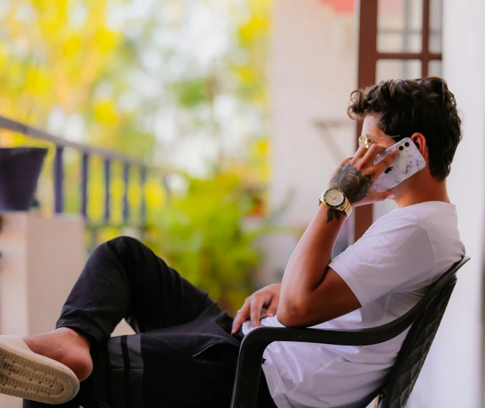 a man sitting in a chair while talking on a cell phone