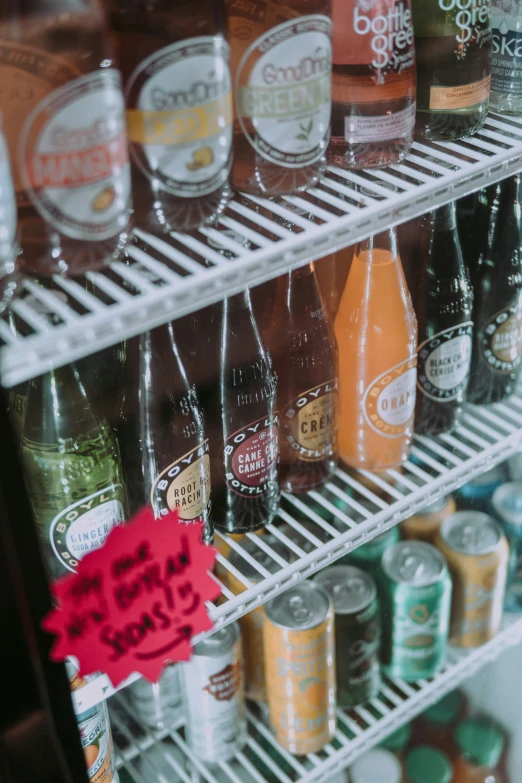 several rows of cold drinks sitting on a refrigerator